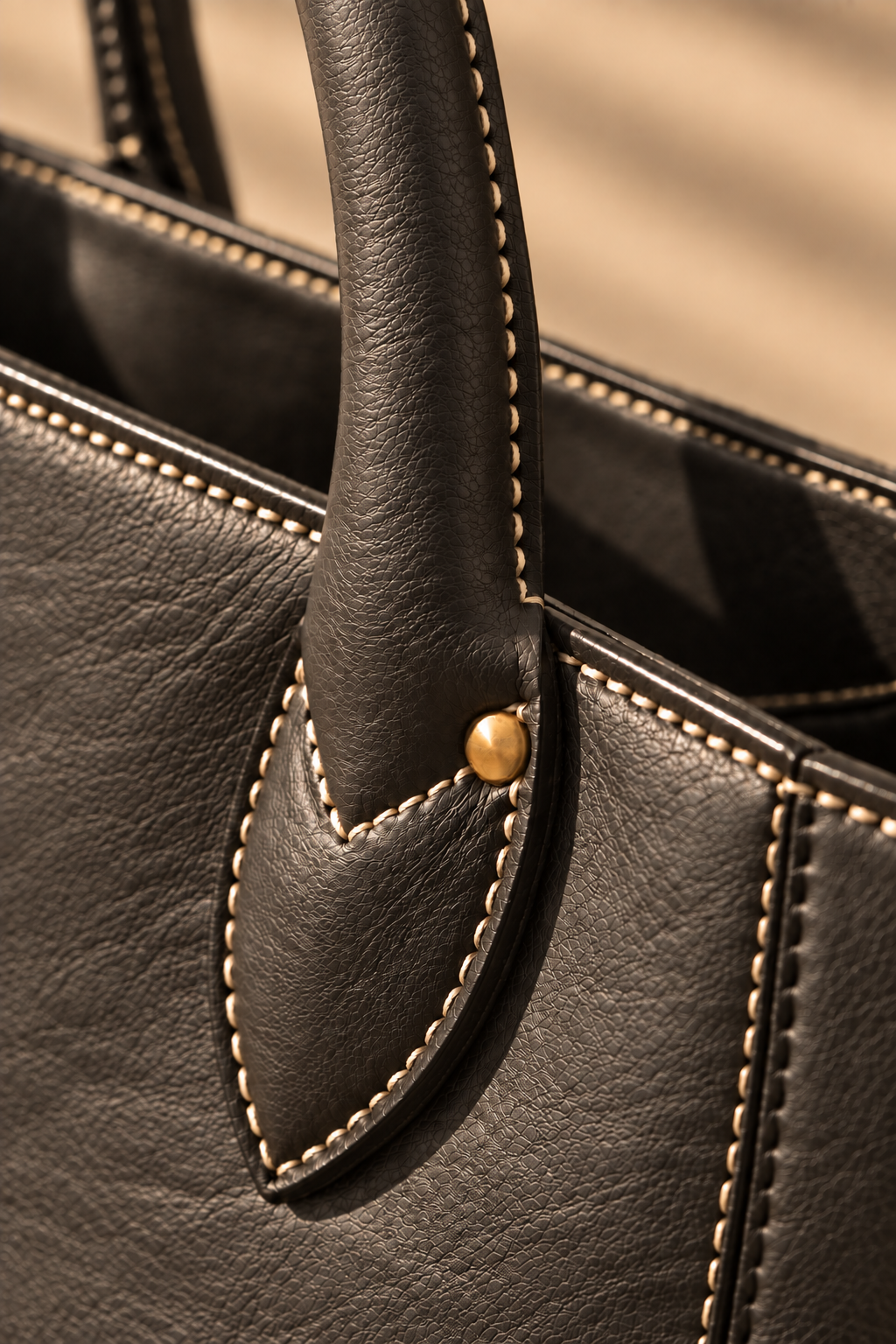 Hand stitched edge and brass rivet on the Marlow charcoal leather tote bag