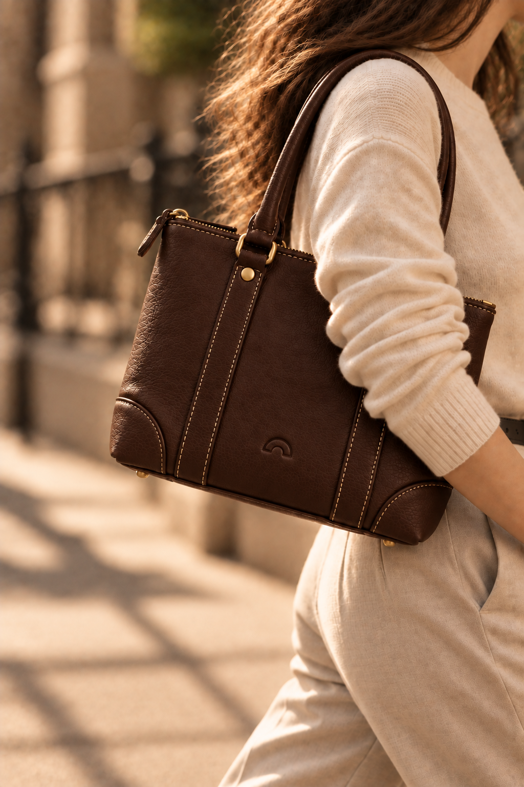 The Juno chocolate small leather tote worn on the shoulder